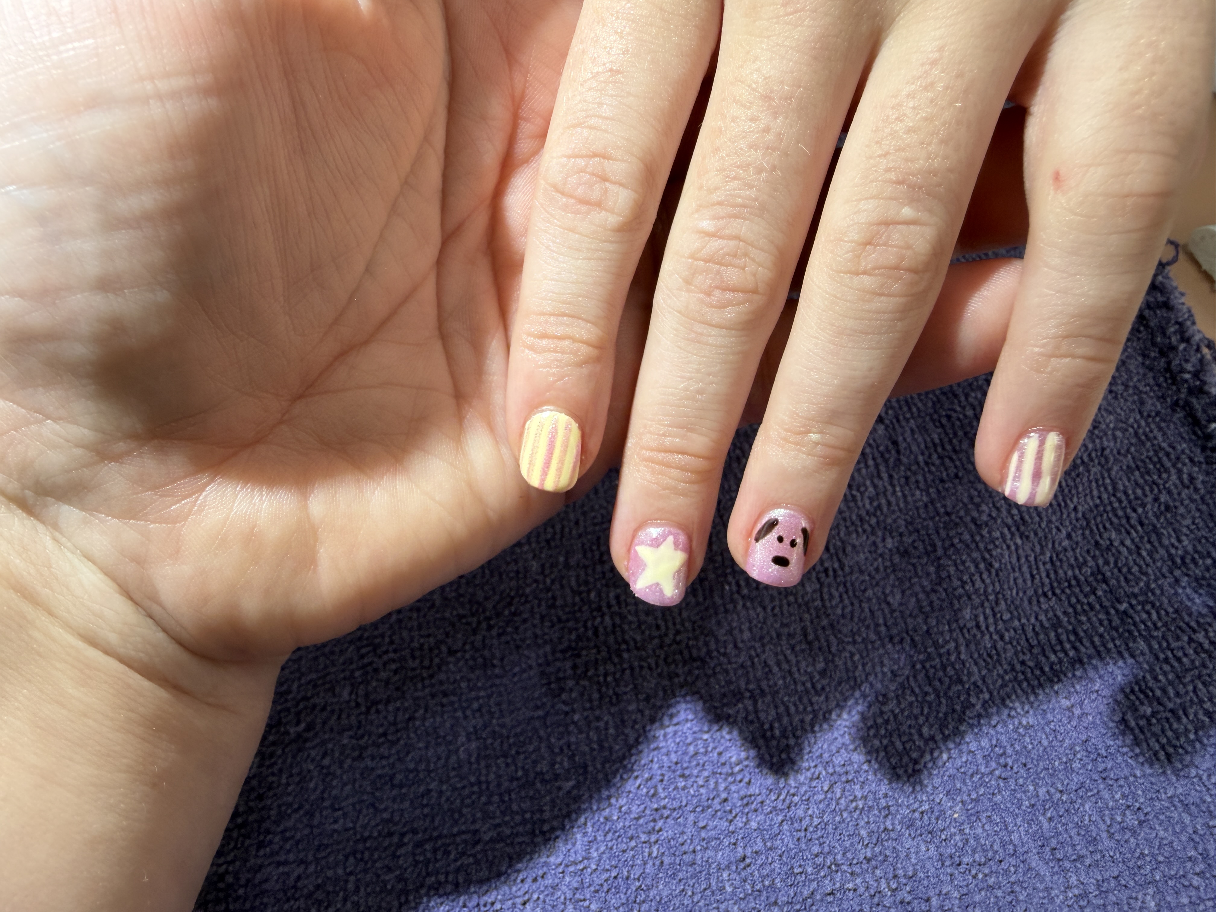 Soft yellow and pink nail art with small smiley face details