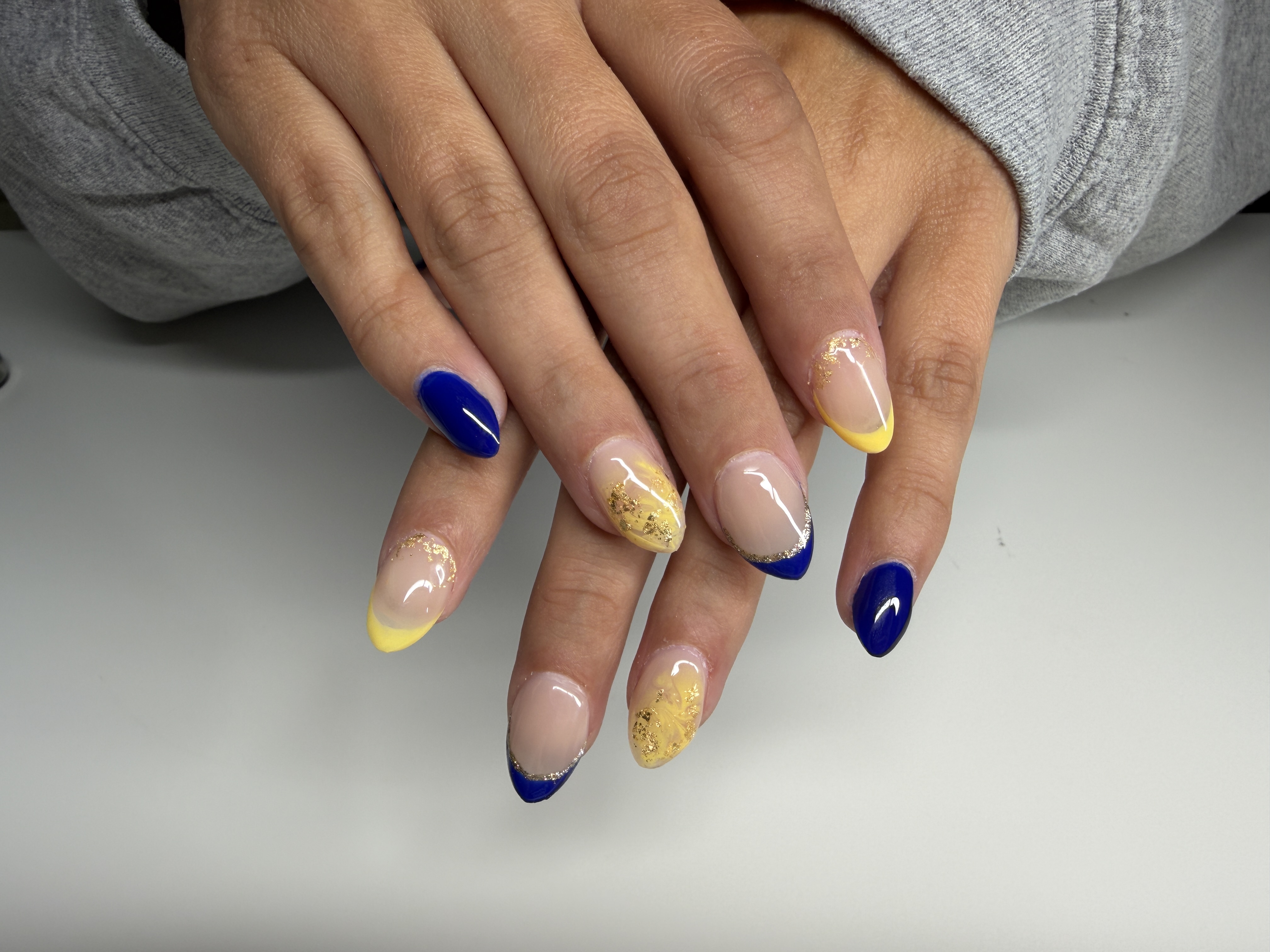 Blue and yellow gel nails with marbled accent nails